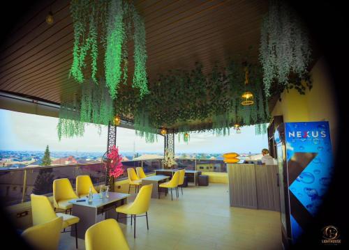 a restaurant with yellow chairs and tables and a large window at Lighthouse Inn and suites in Ibadan