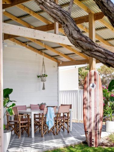 a wooden patio with a table and a surfboard at Stylish Shack Falcon Bay in Wannanup