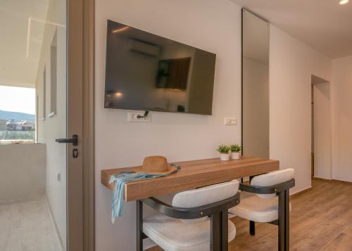 a dining room table with two chairs and a television on the wall at Kiwi Boutique Studios in Kissamos