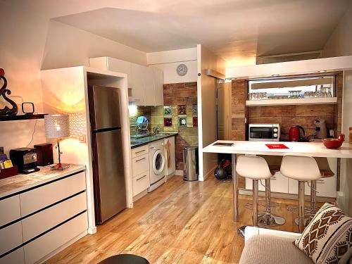 Una cocina con gabinetes blancos y una encimera con taburetes. en 3 étoiles au bord de l'eau, en La Seyne-sur-Mer