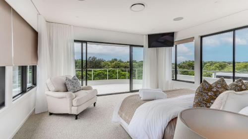 a bedroom with a bed and a chair and windows at Sandcastles in Casuarina