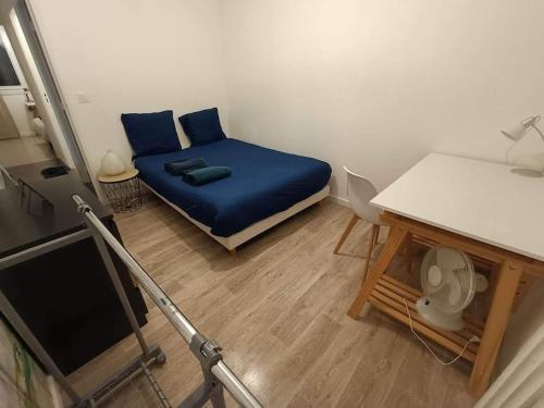 Cette petite chambre comprend un lit bleu et une table. dans l'établissement Appartement 3 chambres - Drapeau, à Dijon