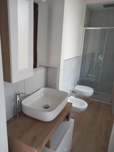 a white bathroom with a sink and a toilet at Downtown Roof in Como