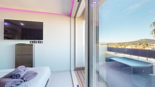 une chambre avec un balcon avec un lit et une fenêtre dans l'établissement Village Naturiste Cap d'Agde, Studio Luxe Port Nature 7, au Cap d'Agde