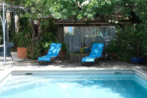 a pair of blue chairs and a swimming pool at jolie location, maison avec piscine et joli jardin fleuri, à oppède dans le luberon en provence – 6 personnes in Oppède