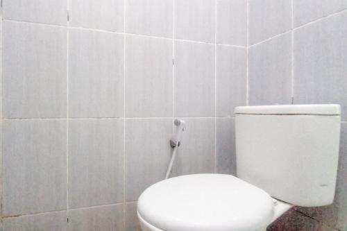 a bathroom with a white toilet in a tiled wall at Kulonprogo Guesthouse Mitra RedDoorz in Temon