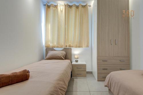 a bedroom with two beds and a dresser and a window at Modern 3BR home with Balcony in Central Msida by 360 Estates in Msieraħ