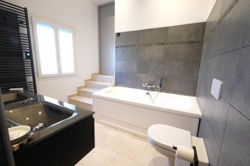 une salle de bain avec une baignoire, un lavabo et des toilettes dans l'établissement vacation rental with pool and poolhouse, close to arles in moulès- sleeps 8, à Moulès