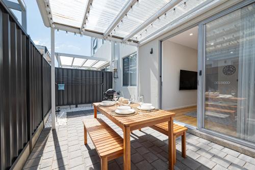 een patio met een houten tafel en stoelen bij Chic Flinders Park Getaway in Adelaide