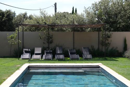 a group of chairs sitting next to a swimming pool at charming villa with heated pool, 14 people, located in aureille, near les baux de provence, in the alpilles in Aureille
