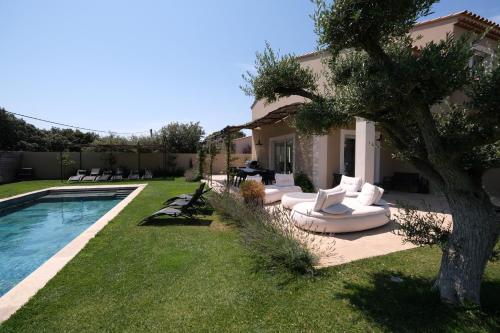 a yard with a pool with white couches and a tree at charming villa with heated pool, 14 people, located in aureille, near les baux de provence, in the alpilles in Aureille