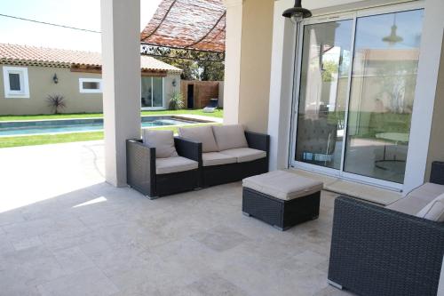 a patio with two chairs and a couch and a table at charming villa with heated pool, 14 people, located in aureille, near les baux de provence, in the alpilles in Aureille