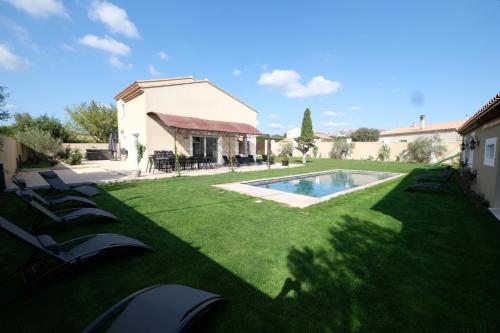 a yard with lounge chairs and a swimming pool at charming villa with heated pool, 14 people, located in aureille, near les baux de provence, in the alpilles in Aureille