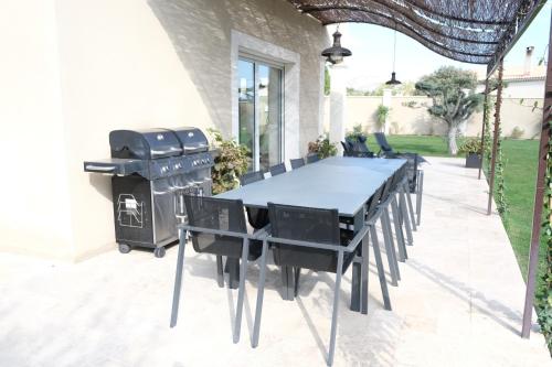 a patio with a table and a grill at charming villa with heated pool, 14 people, located in aureille, near les baux de provence, in the alpilles in Aureille