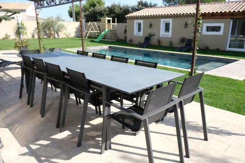 a table and chairs with a pool in a backyard at charming villa with heated pool, 14 people, located in aureille, near les baux de provence, in the alpilles in Aureille