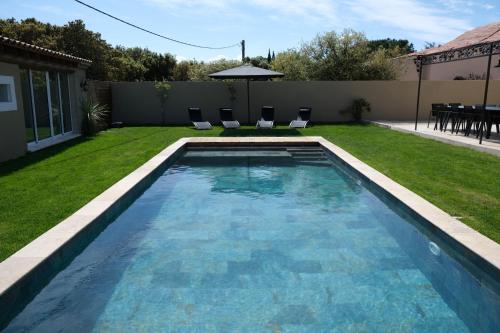 a swimming pool in a yard with chairs and an umbrella at charming villa with heated pool, 14 people, located in aureille, near les baux de provence, in the alpilles in Aureille
