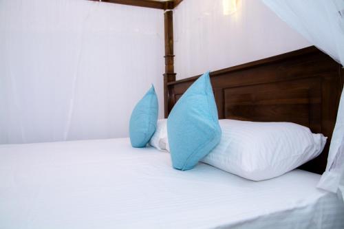 two blue pillows sitting on top of a bed at Samanmali Apartment in Unawatuna