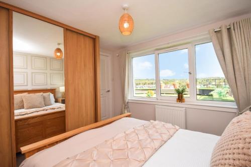 une chambre avec un lit et un grand miroir dans l'établissement Laudervale East Penthouse Loch Lomond, à Balloch