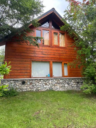 Cabaña de madera con pared de piedra en Huet Huet, en Villa La Angostura