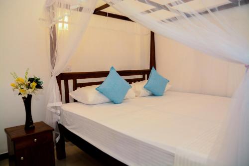 a bedroom with a bed with blue and white pillows at Samanmali Apartment in Unawatuna