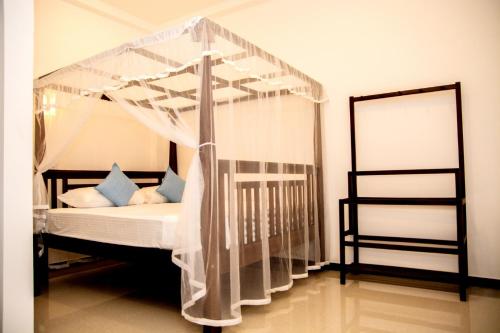 a bedroom with a canopy bed with blue pillows at Samanmali Apartment in Unawatuna