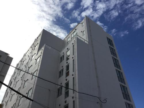 a tall white building with a sky in the background at Hotel Peace Island Miyakojima in Miyako Island