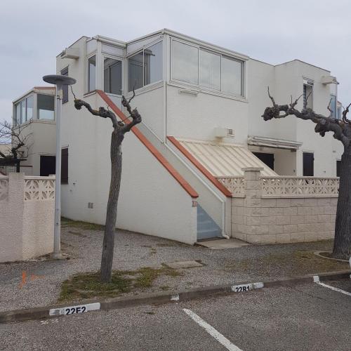 une maison blanche avec un escalier rouge dans un parking dans l'établissement Appartement cosy LE BARCARES, au Barcarès