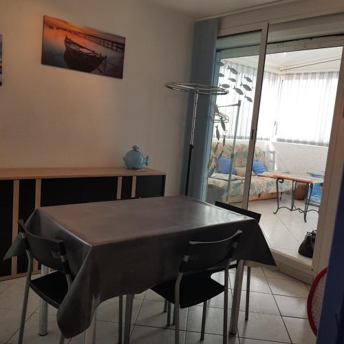 une table et des chaises dans une pièce avec une fenêtre dans l'établissement Appartement cosy LE BARCARES, au Barcarès