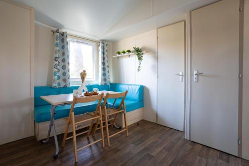 a dining room with a blue bench and a table and chairs at Club del Sole Adriano Family Collection in Punta Marina