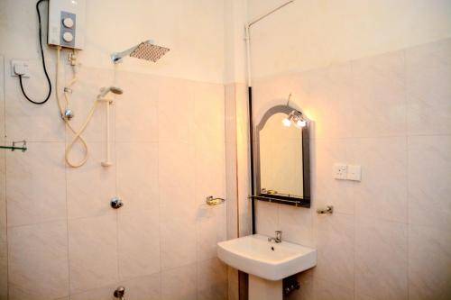 a bathroom with a sink and a shower with a mirror at Samanmali Apartment in Unawatuna