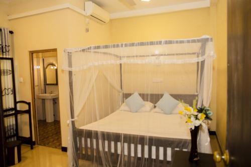 a bedroom with a canopy bed with pillows at Samanmali Apartment in Unawatuna