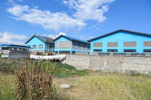a row of blue houses behind a stone wall at Sangare Gardens- Book Now Enjoy Free Farm Tour in Mweiga