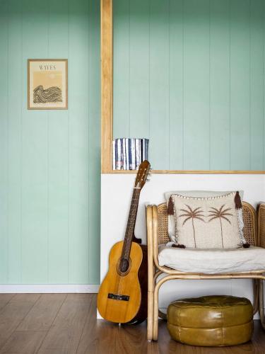 a guitar in a room with a chair and a pillow at Stylish Shack Falcon Bay in Wannanup