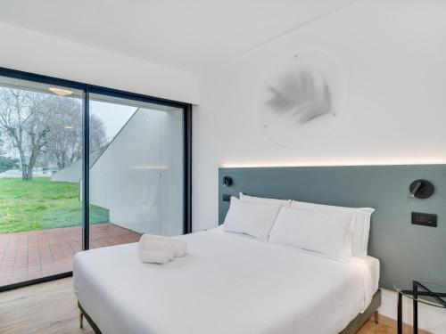 a bedroom with a white bed and a large window at B&B HOTEL Alba in Alba