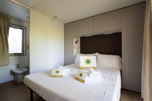 a bedroom with a white bed with two boxes on it at Club del Sole Adriano Family Collection in Punta Marina