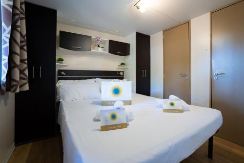 a bedroom with a white bed with two boxes on it at Club del Sole Adriano Family Collection in Punta Marina