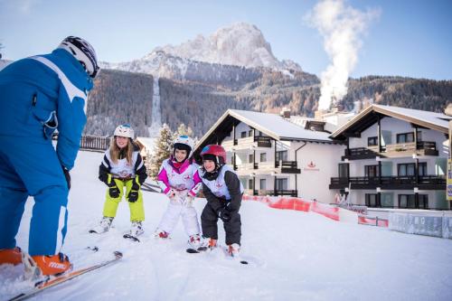 a group of three children on skis in the snow at Biancaneve Family Hotel in Selva di Val Gardena