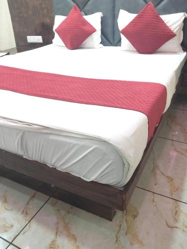 a bed with red and white pillows on it at Hotel Raj Palace in Ahmedabad