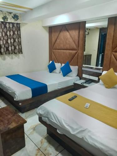 a hotel room with two beds and a mirror at Hotel Raj Palace in Ahmedabad