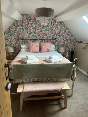 a bedroom with a large bed with pink flowers at Beautiful Bell Cottage Heart of Bridgnorth Walk Everywhere in Bridgnorth