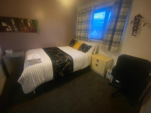 a bedroom with a bed and a chair and a window at Harbury Lodge in Scotstoun West Station
