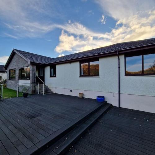a white house with a large wooden deck at Sachsblick in Lochgoilhead