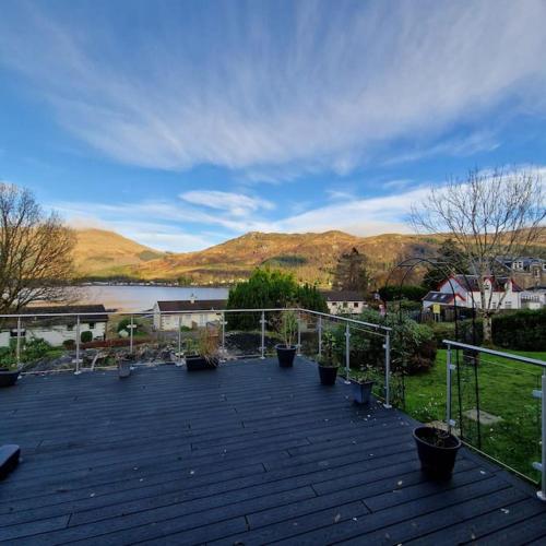 a deck with potted plants and a view of a lake at Sachsblick in Lochgoilhead