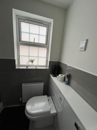 a bathroom with a white toilet and a window at Cosy family home in Buckingham in Buckinghamshire