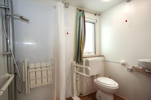 a white bathroom with a toilet and a sink at Club del Sole Adriano Family Collection in Punta Marina