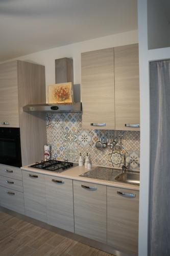 a kitchen with white cabinets and a sink and a stove at A Casa di Elsa in Sonnino