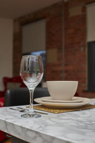 a table with a wine glass and a bowl on it at BV Aparthotel Stays in the Heart of Barnsley Town Centre in Barnsley