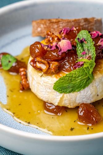 a white plate with a sandwich with nuts and sauce at Villa Promenade in Burgas City