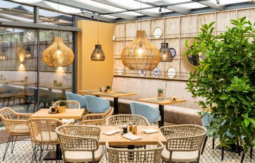 a restaurant with wooden tables and chairs and potted plants at Villa Promenade in Burgas City