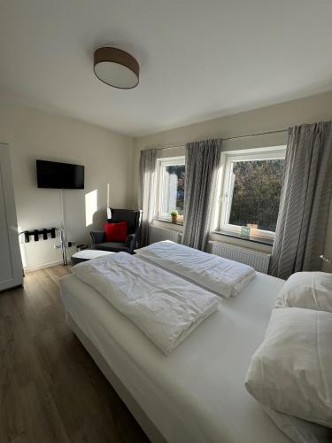 a bedroom with a large white bed and two windows at Ferienwohnung Sommerlinde in Altleiningen
